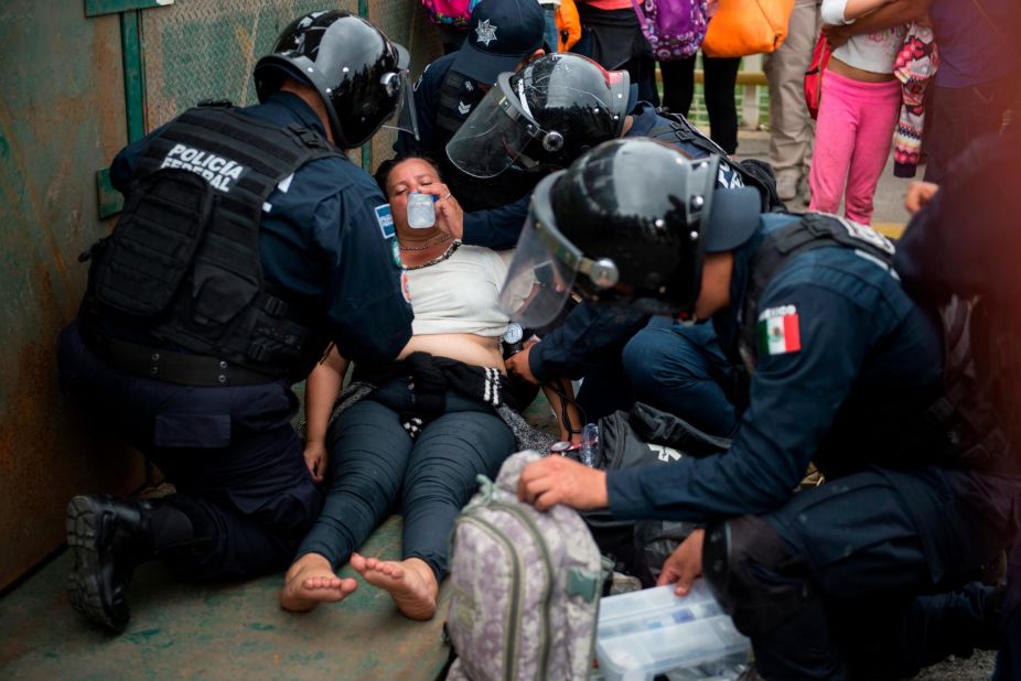 Mexican paramedics help a Honduran woman who fainted after crossing the border between Guatemala and Mexico on Saturday.
