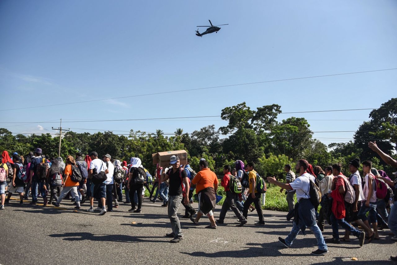 A Mexican Federal Police helicopter flies over migrants heading in a caravan to the United States, on the road linking Ciudad Hidalgo and Tapachula in Mexico.