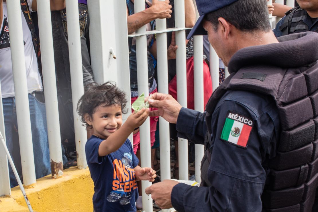 A young boy named Carlitos plays with a Mexican federal police officer as he waits with his mom on the bridge from Guatemala.
