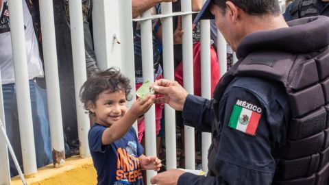 A young boy named Carlitos plays with a Mexican federal police officer as he waits with his mom on the bridge from Guatemala.