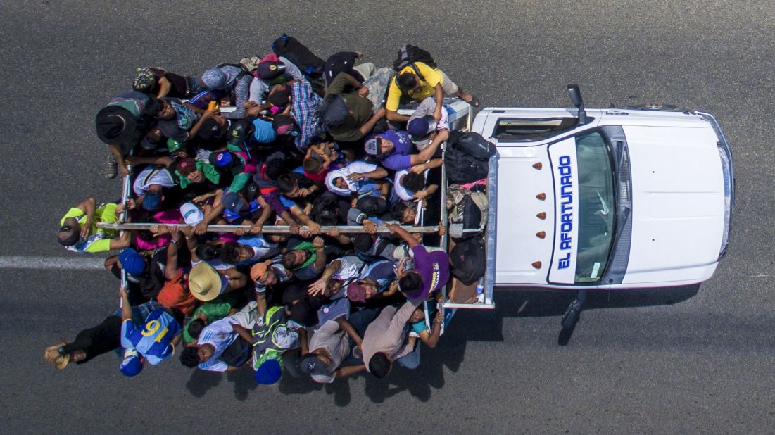 Migrants ride on the back of a truck heading to the US border from the outskirts of Tapachula, Mexico, on Monday, October 22. The majority of migrants made their way on foot. But some also flagged down cars and trucks passing by and piled onto any vehicle that would take them.