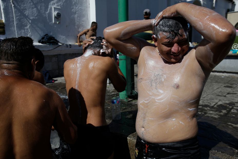 Migrant men bathe using water from a fire hydrant at the main plaza in Tapachula, Mexico. 