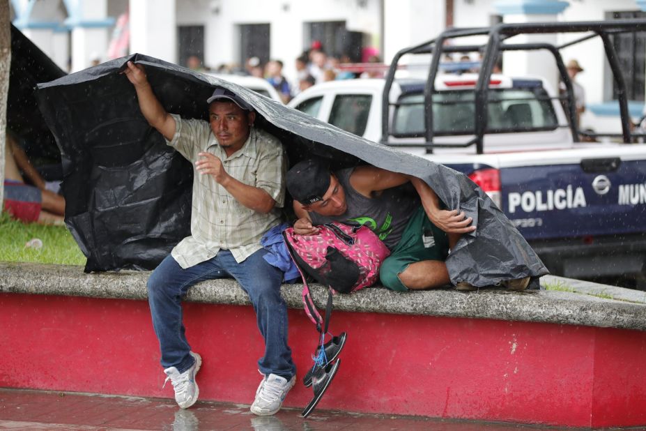 Migrants take shelter from the weather under a tarp as they rest in the town of Huixtla, Mexico, on October 22.