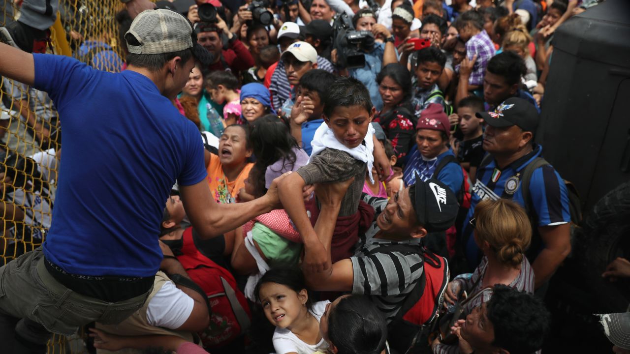 CIUDAD TECUN UMAN, GUATEMALA - OCTOBER 19:  Children in the migrant caravan are lifted over a gate at the Guatemala-Mexico border on October 19, 2018 in Ciudad Tecun Uman, Guatemala. The caravan of thousands of immigrants, most from Honduras, pushed past Guatemalan police before clashing with Mexican riot police.  (Photo by John Moore/Getty Images)