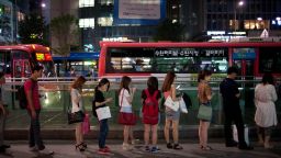 People wait for a bus on a street in the Gangnam district of Seoul on July 5, 2013. One of Asia's most affluent countries, South Korea is the region's third largest economy fuelled by the longest working hours in the world, according to a 2012 study. However the number of foreign workers in the the country is expected to swell as migrants fill the jobs that increasingly considered as the '3d's'; dirty, dangerous and difficult, or demeaning -- mainly in manufacturing and construction. AFP PHOTO / Ed Jones        (Photo credit should read Ed Jones/AFP/Getty Images)