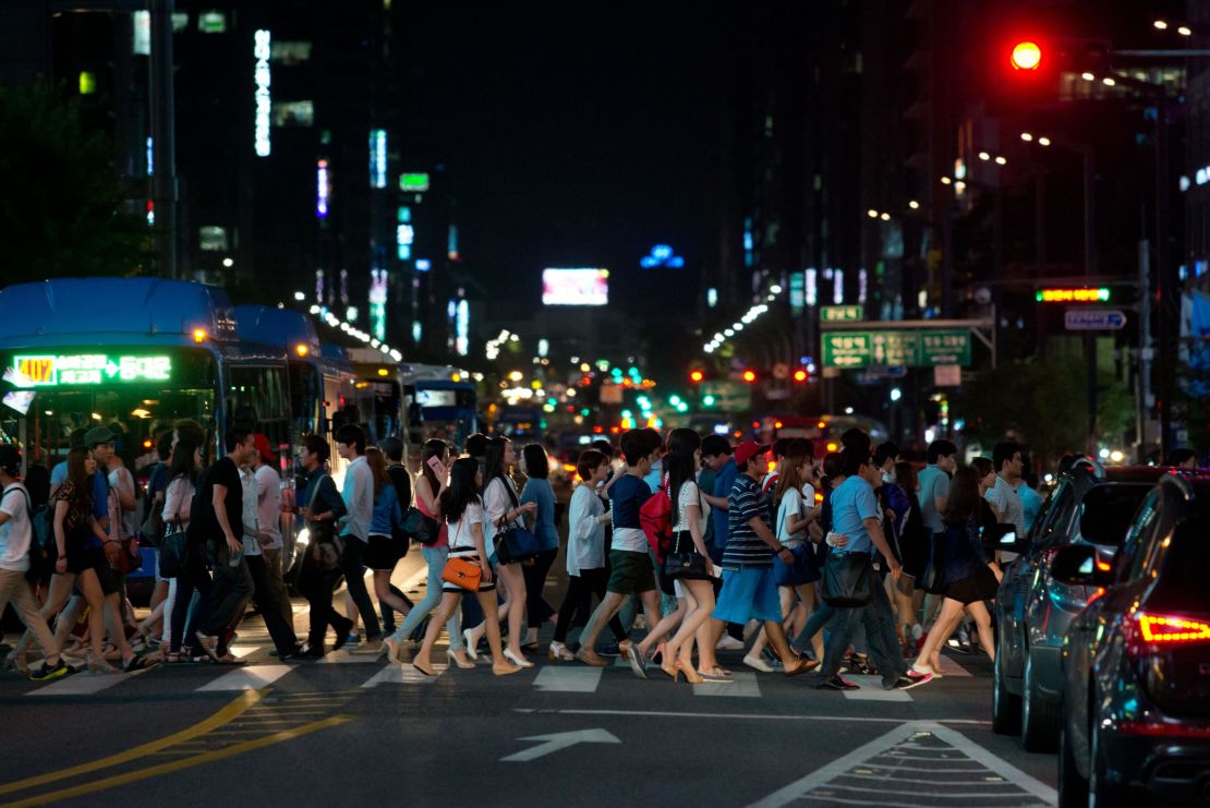 Pedestrians cross a road in the Gangnam district of Seoul. South Korea has some of the longest working hours in the world.