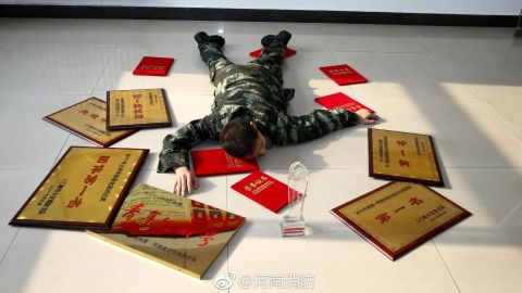 A Henan Fire Department employee lies among the awards he has won for his work, the government body's response to the "Flaunt your wealth" campaign on Chinese social media.