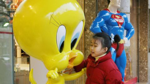 A young Chinese girl plays on a 'Tweety Bird' statue outside a newly opened Warner Brothers store on the Nanjing Road shopping street in Shanghai, 09 February 2006. 