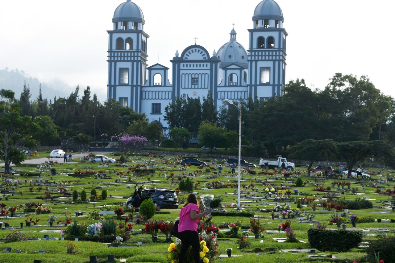 A woman takes flowers to the grave of a relative during the Day of the Dead at a cemetery in Tegucigalpa, Honduras, on November 2, 2017.