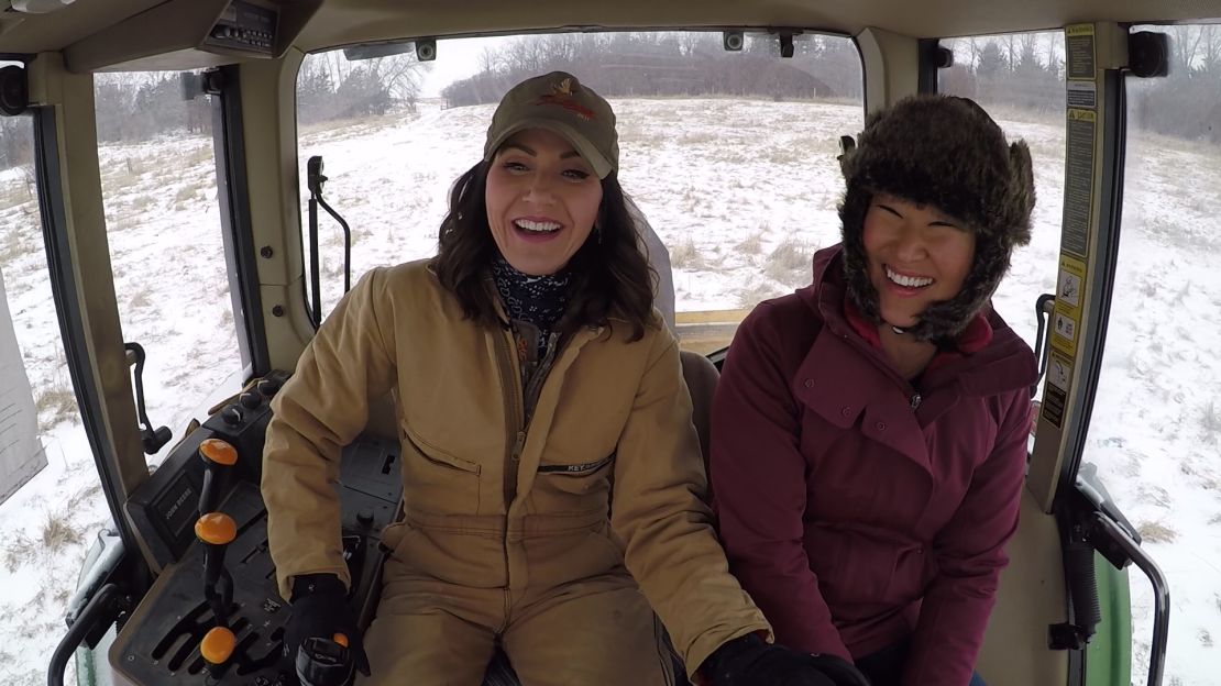 Kristi Noem, left, was far more at home in the icy tractor cab than reporter Kyung Lah.