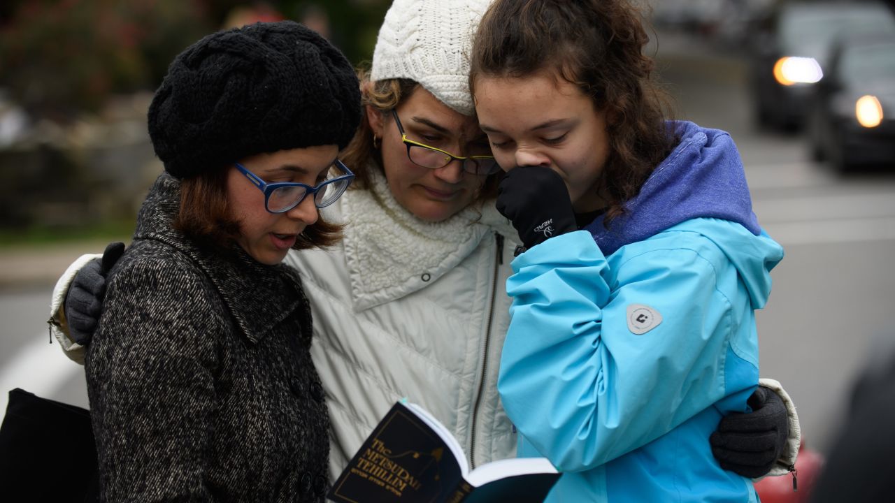 Tammy Hepps, Kate Rothstein and her daughter, Simone Rothstein, 16, pray from a prayerbook a block away from the site of a mass shooting at the Tree of Life Synagogue in the Squirrel Hill neighborhood on October 27, 2018 in Pittsburgh, Pennsylvania.