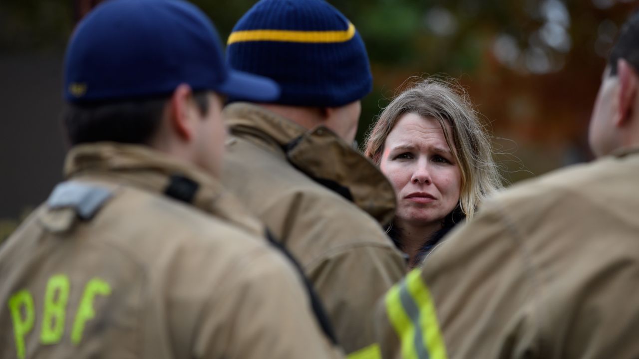 An unidentified woman asks for a status update from firefighters a block away from the shooting.