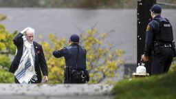 A man holds his head as he's escorted by police out of the Tree of Life Congregation synagogue where multiple people were killed Saturday, Oct. 27, 2018, in the Squirrel Hill section of Pittsburgh. (Alexandra Wimley/Pittsburgh Post-Gazette via AP)