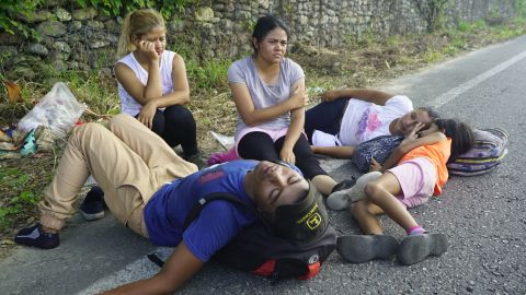 Iris, who did not want to give her last name, sits holding her head as her family collapses in exhaustion on the road to Arriaga, Mexico.