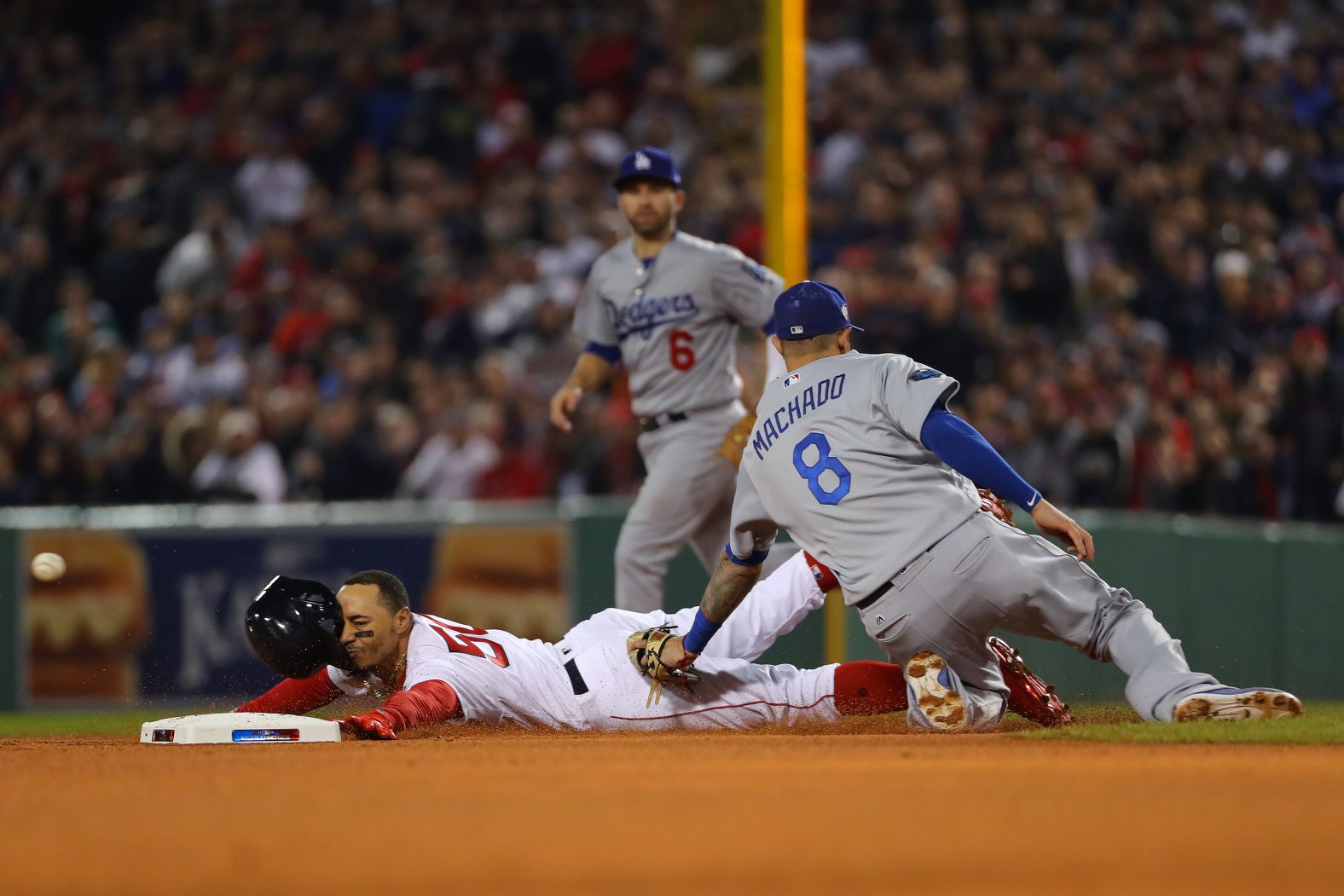 Mookie Betts of the Boston Red Sox steals second base ahead of the tag from Manny Machado of the Los Angeles Dodgers in the first inning of Game 1.  As part of Taco Bell's "Steal a Base, Steal a Taco" promotion, Betts' stolen base won everyone in America a free Doritos Locos Taco redeemable on November 1.