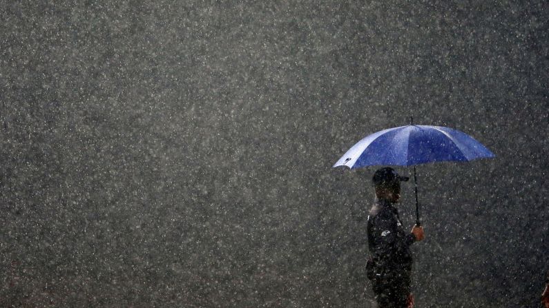 A match official is seen in the rain during a cricket match between Sri Lanka and England on Tuesday, October 23. The match was being played in Colombo, Sri Lanka.