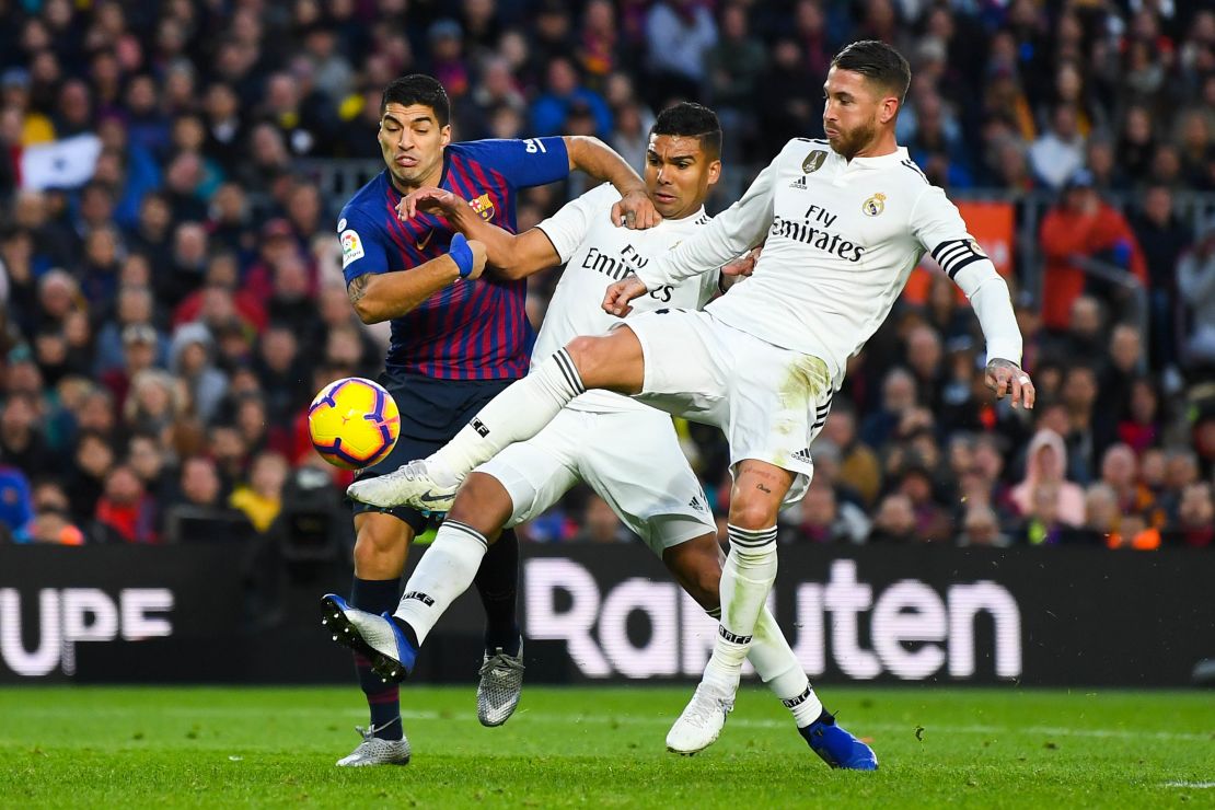 Barcelona's Luis Suarez  competes for the ball with Real's Carlos Enrique Casimiro and Sergio Ramos.