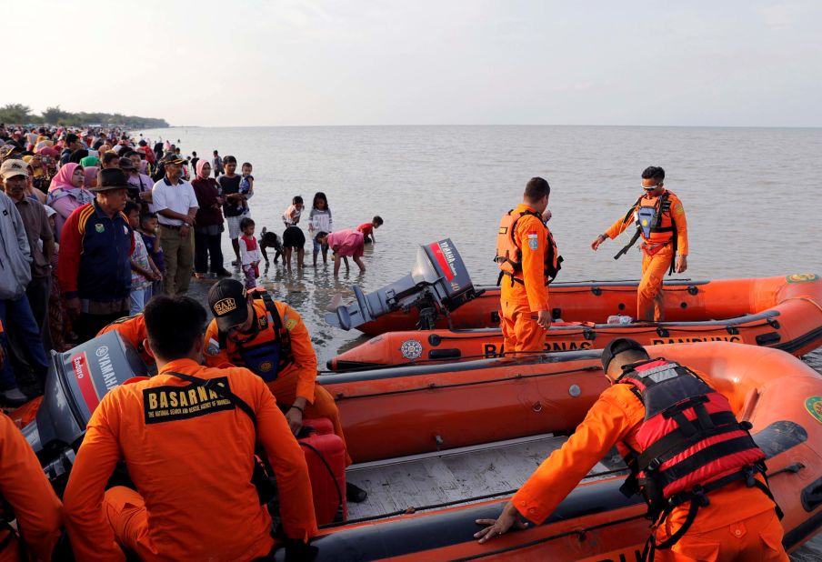 People gather on the beach as a rescue team prepares to leave the coast of Karawang.