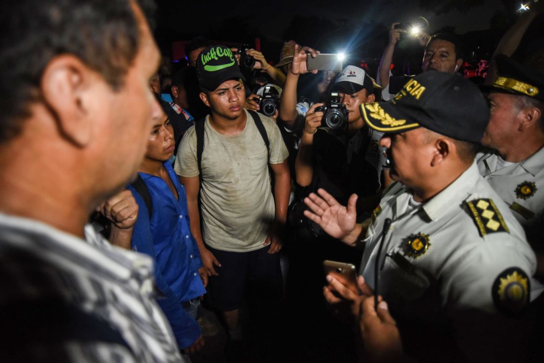 Honduran migrants taking part in a new caravan heading to the US, talk with Guatemalan police officers on their arrival to Chiquimula, Guatemala, on October 22, 2018. - US President Donald Trump on Monday called the migrant caravan heading toward the US-Mexico border a national emergency, saying he has alerted the US border patrol and military. 