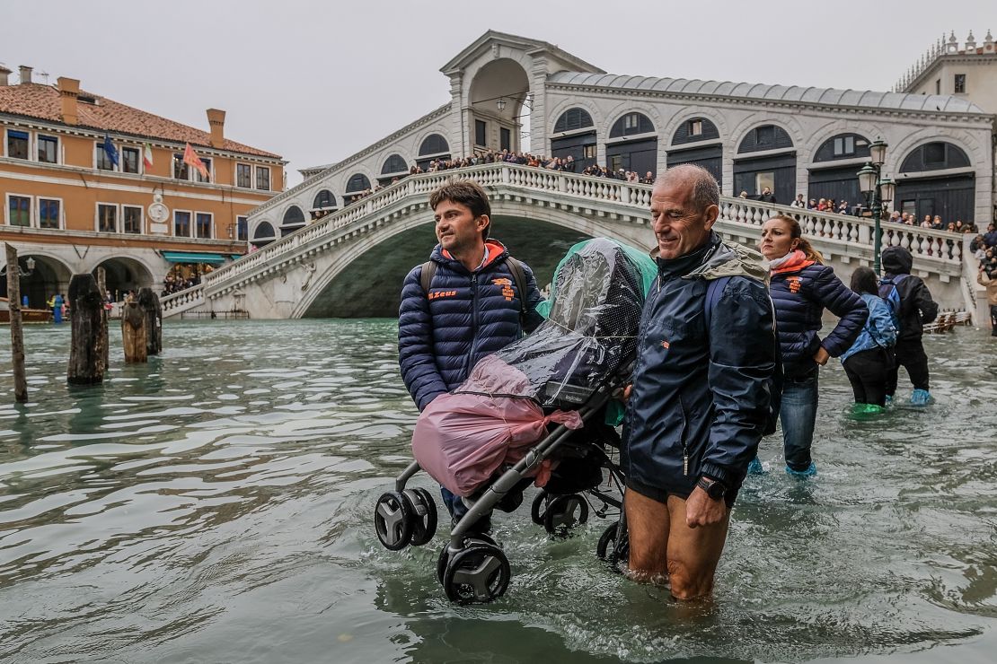 Tourists carry a stroller through the floodwaters near Venice's Rialto Bridge on Monday.