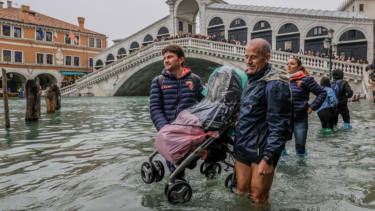 Tourists carry a stroller through the floodwaters near Venice's Rialto Bridge on Monday.