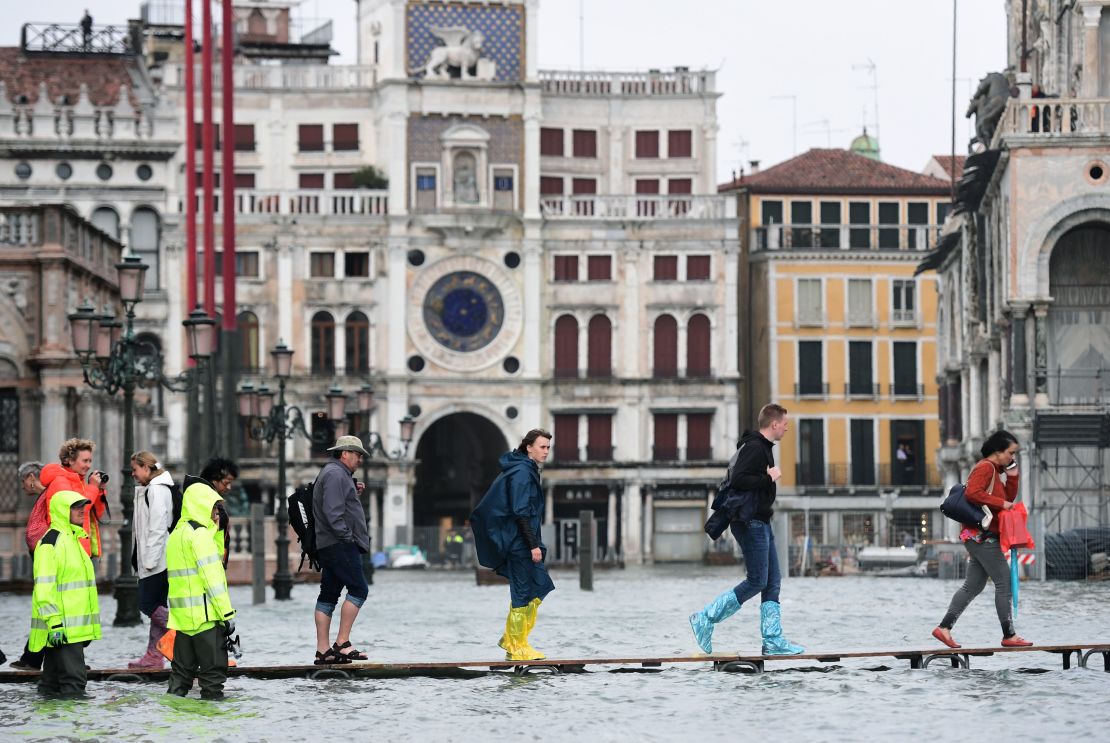 People cross the flooded St. Mark's Square on a raised walkway Monday.