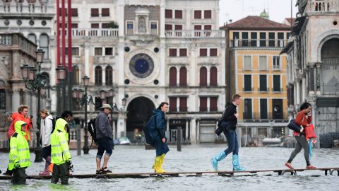 People cross the flooded St. Mark's Square on a raised walkway Monday.