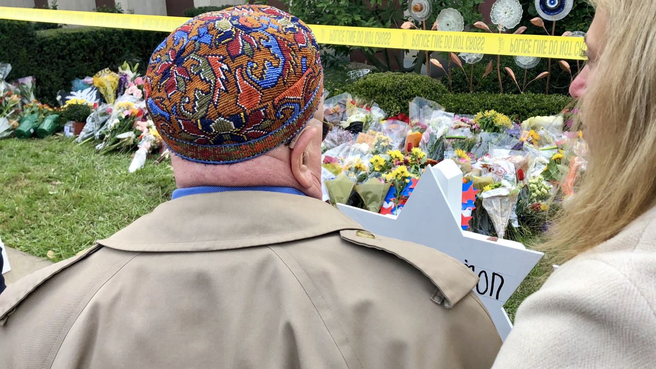 Judah Samet stands at the synogague's makeshift grave markings for the 11 killed now surrounded by police tape, mourners flowers.