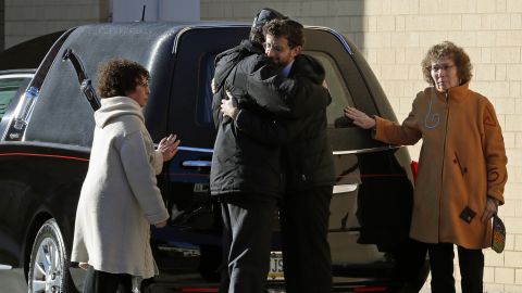 Mourners embrace after the hearse carrying the casket of Dr. Jerry Rabinowitz arrives Tuesday morning outside the Jewish Community Center in Pittsburgh.