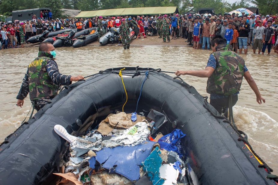 Soldiers drag ashore an inflatable raft containing debris from the plane.