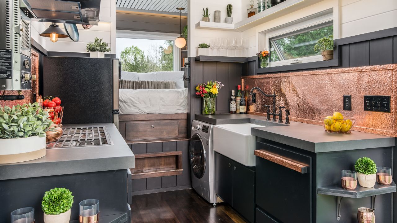 The full-sized kitchen, with king sized bed just beyond, in the Escher model tiny home from New Frontier Tiny Homes.
