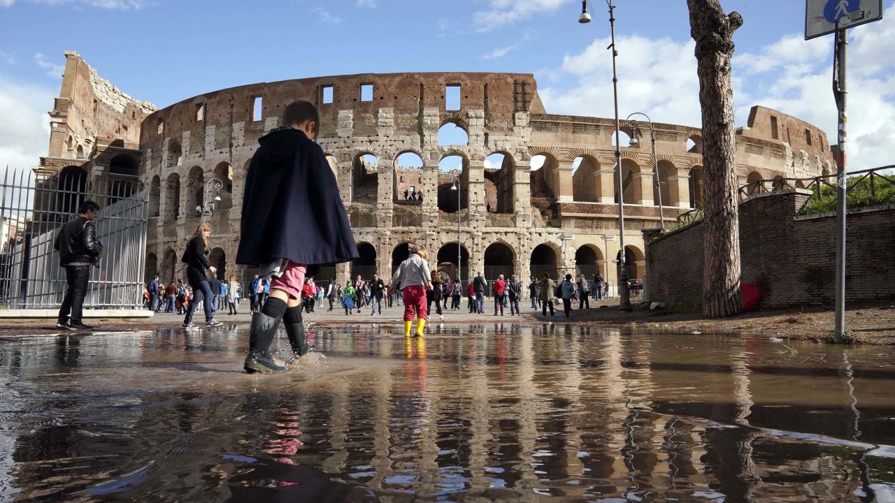 Children play in a puddle by the ancient Colosseum in Rome on Tuesday, a day after strong winds and rain hit the city.
