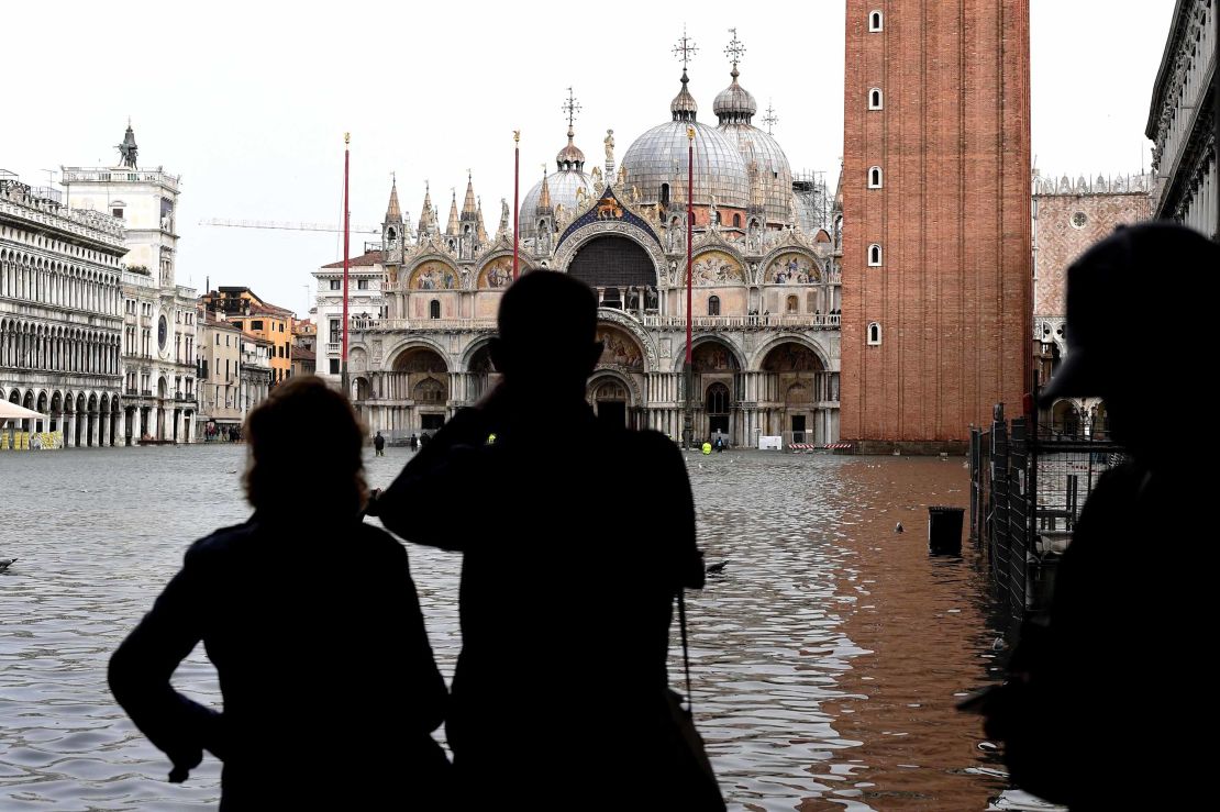 Tourists take pictures in the flooded St Mark's Square during a high-water alert in Venice on October 29, 2018.