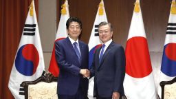 Japanese Prime Minister Shinzo Abe (left) and South Korean President Moon Jae-in shake hands ahead of their talks in New York on Sept. 25, 2018.