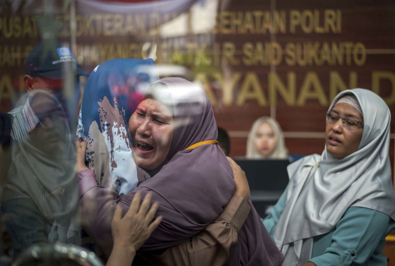 Victims' relatives embrace at a police hospital in Jakarta.