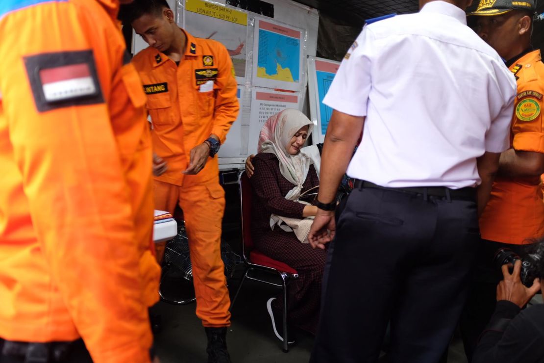 A woman who came to the port to look at the items cries as she is surrounded by officials.