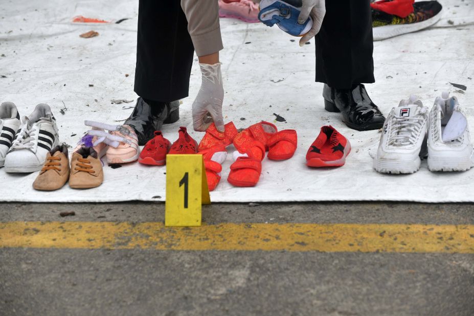 A police officer arranges shoes recovered during search operations.