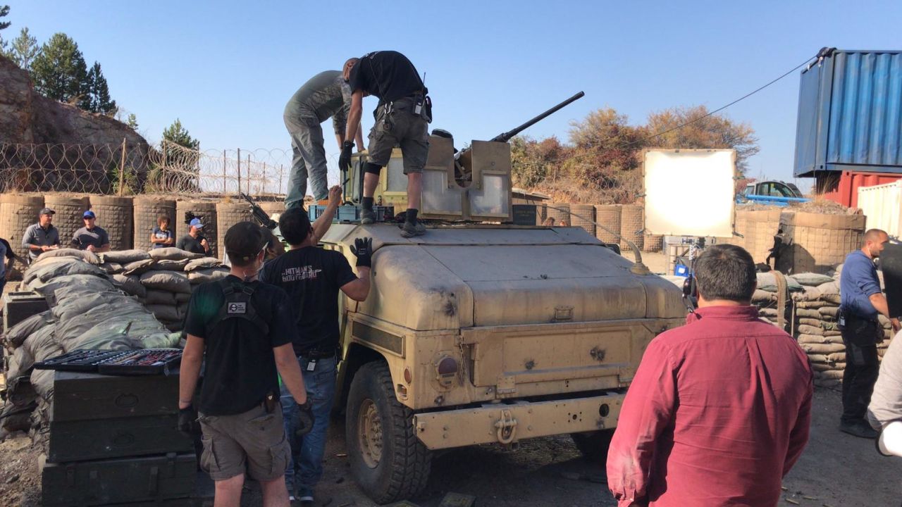 The film crew attend to an army tank on set.