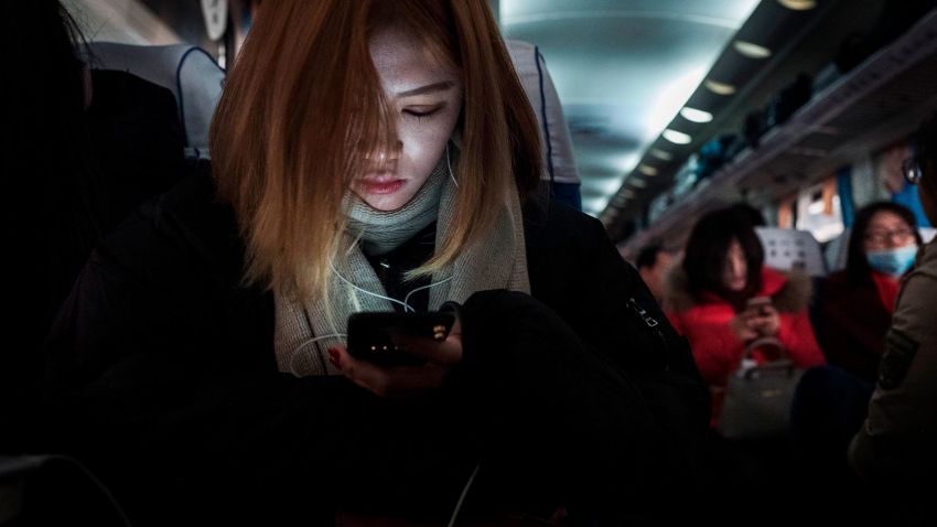 BEIJING, CHINA - JANUARY 25: A Chinese traveler rests as she holds her mobile phone on a crowded train between Beijing and Shijiazhuang, on January 25, 2017 in Hebei province, northern China. Millions of Chinese will travel home to visit families in what is often called the largest human migration during the Spring Festival holiday period that begins with the Lunar New Year on January 28, 2017. (Photo by Kevin Frayer/Getty Images)