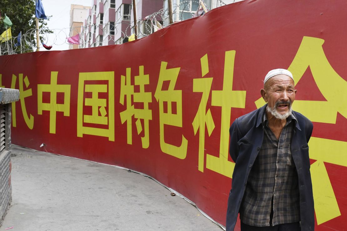 Photo taken on July 2, 2018, shows a man walking past a wall bearing a China Communist Party slogan in Kashgar.