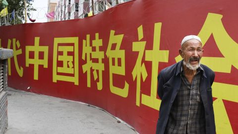 Photo taken on July 2, 2018, shows a man walking past a wall bearing a China Communist Party slogan in Kashgar in the country's Xinjiang Uyghur Autonomous Region.