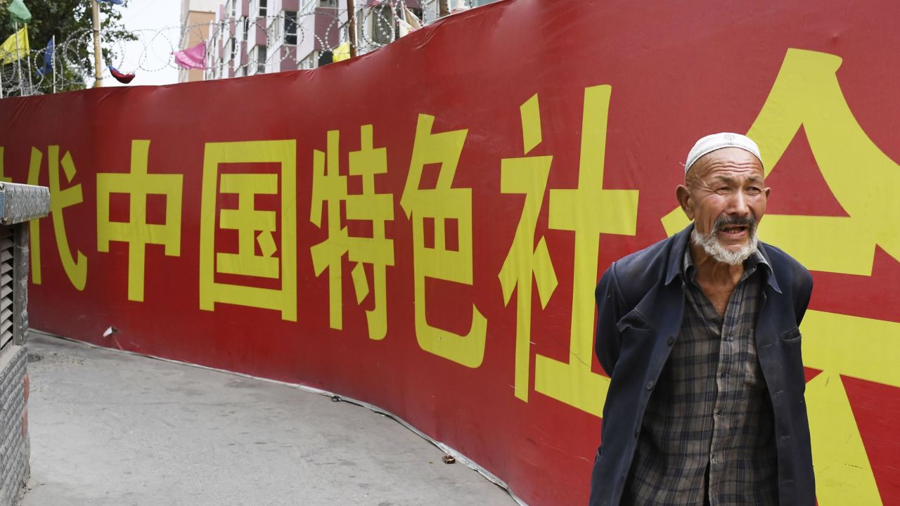 Photo taken on July 2, 2018, shows a man walking past a wall bearing a China Communist Party slogan in Kashgar.