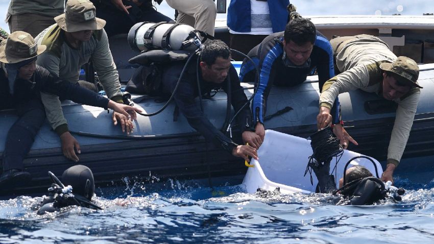 An Indonesian Navy diver (bottom L) holds a recovered "black box" under water before putting it into a plastic container (R) after its discovery during search operations for the ill-fated Lion Air flight JT 610 at sea, north of Karawang in West Java on November 1, 2018. - One black box from the crashed Lion Air jet has been recovered, the head of Indonesia's National Transportation Safety Committee said on November 1, which could be critical to establishing why the brand new plane fell out of the sky. (Photo by ADEK BERRY / AFP)        (Photo credit should read ADEK BERRY/AFP/Getty Images)
