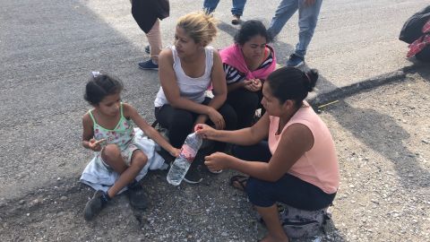 A group of women, including a mother and daughter, rest on the side of the road and share water en route to Juchitán, Oaxaca. 