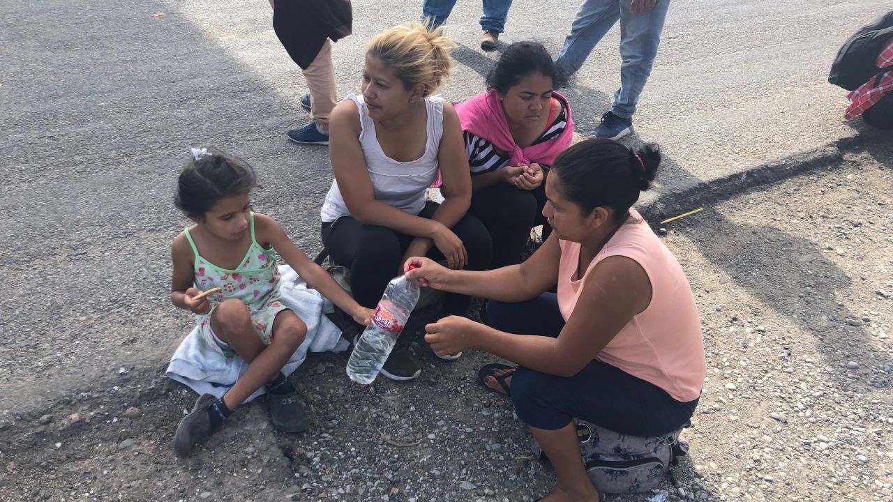 A group of women, including a mother and daughter, rest on the side of the road and share water en route to Juchitán, Oaxaca.