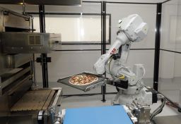 A robot places a pizza into an oven at Zume.