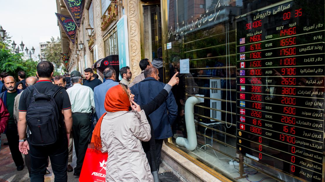 Pedestrians look at currency exchange rates in the window of a store in Tehran on Saturday.