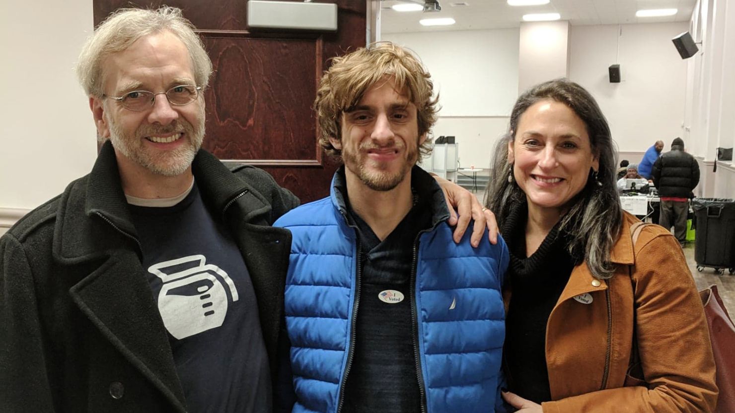 Nathaniel Batchelder proudly wears an "I Voted" sticker after casting an early ballot alongside father Ned Batchelder and mother Susan Senator.