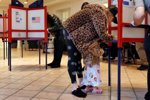 Falcon Wien, 2, huddles under the coat of her mother, Sarah, as she votes in Mount Kisco, New York.