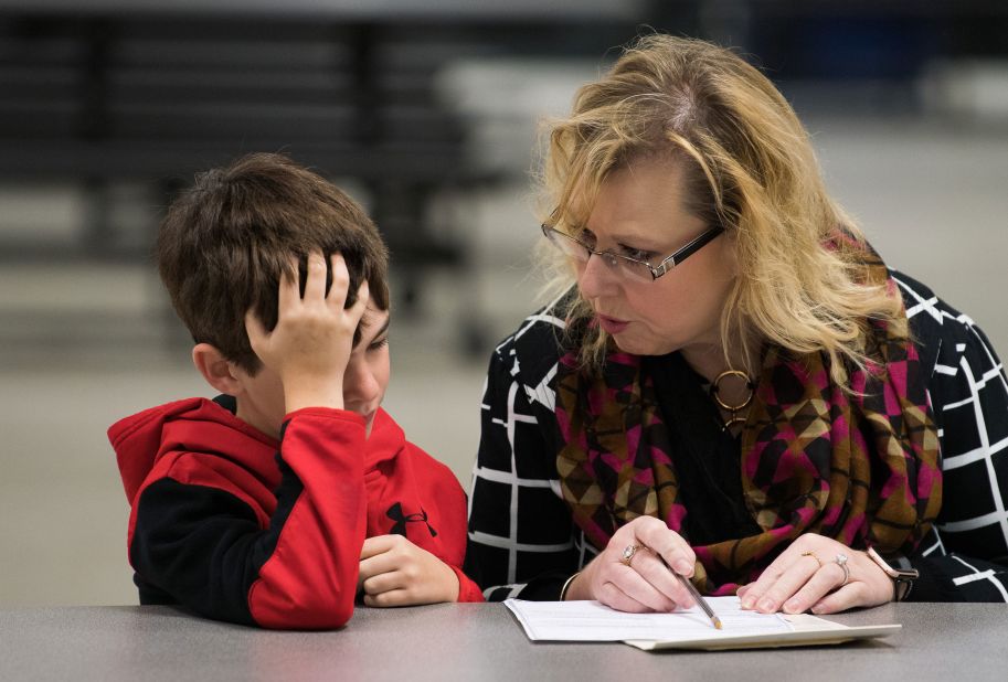A woman shows a boy how to fill out a ballot as she votes in Leesburg, Virginia.